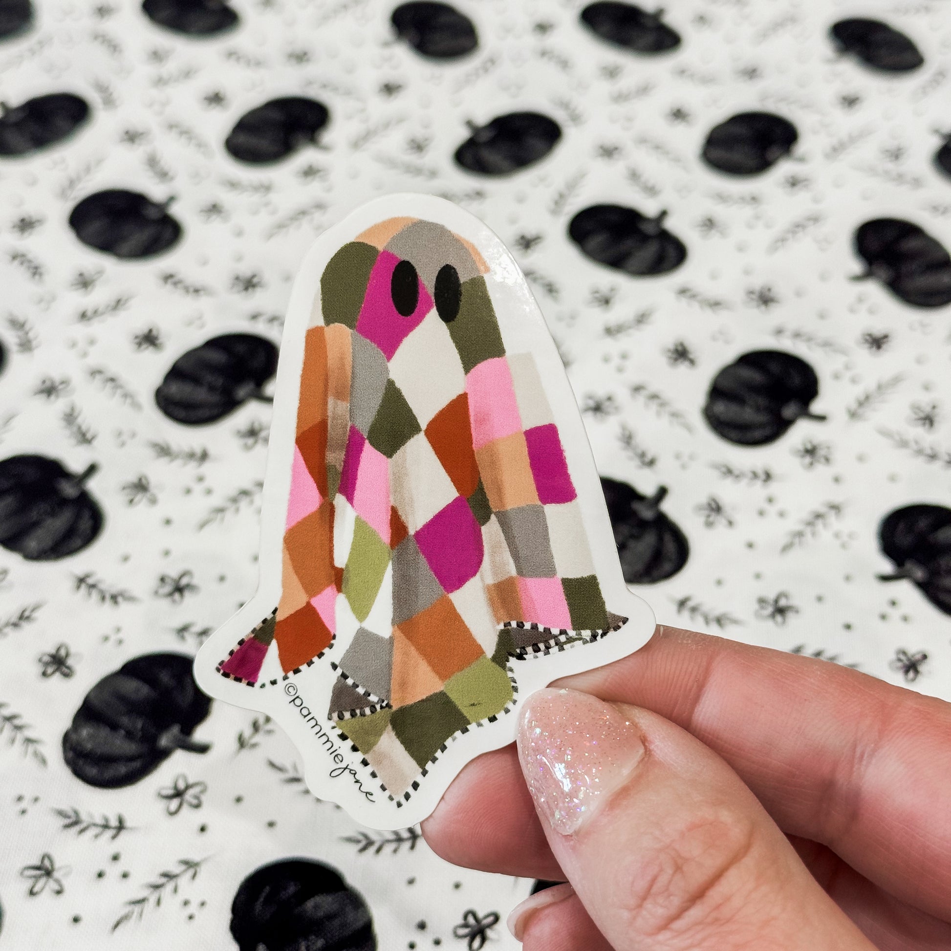 Colorful patterned sticker held by a hand with a decorative background